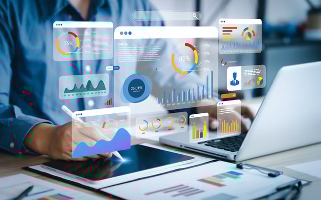 Cette image représente une personne analysant des données variées, sur plusieurs écrans en transparence à l'aide d'une tablette.