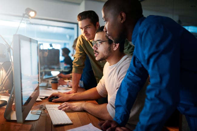 Trois hommes sont devant un écran d'ordinateur et travaillent avec des outils et méthodes de testing