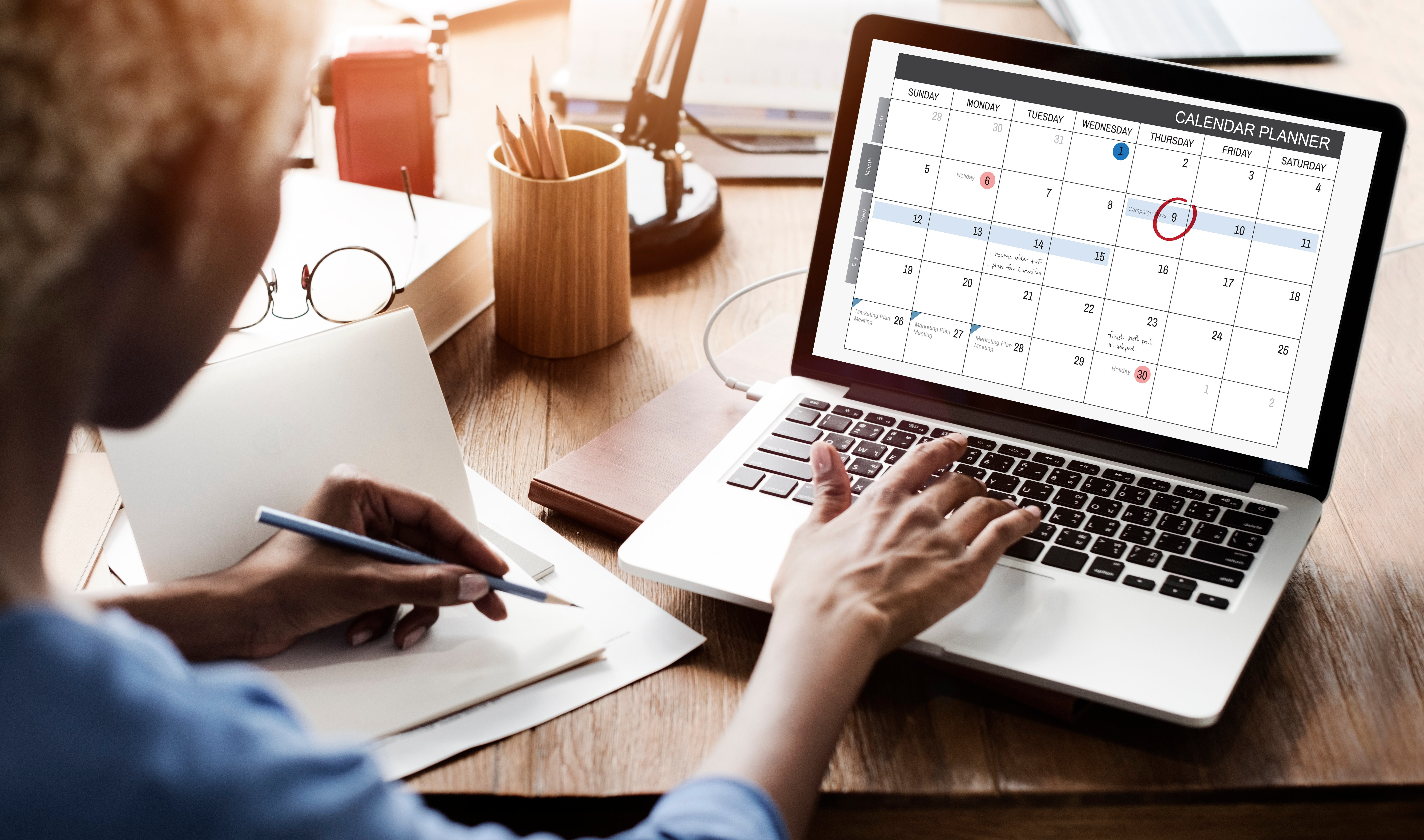 Professionnel consultant un calendrier d'événements cloud sur ordinateur portable avec dates importantes marquées, prenant des notes pour planifier sa participation aux conférences et webinaires tech.