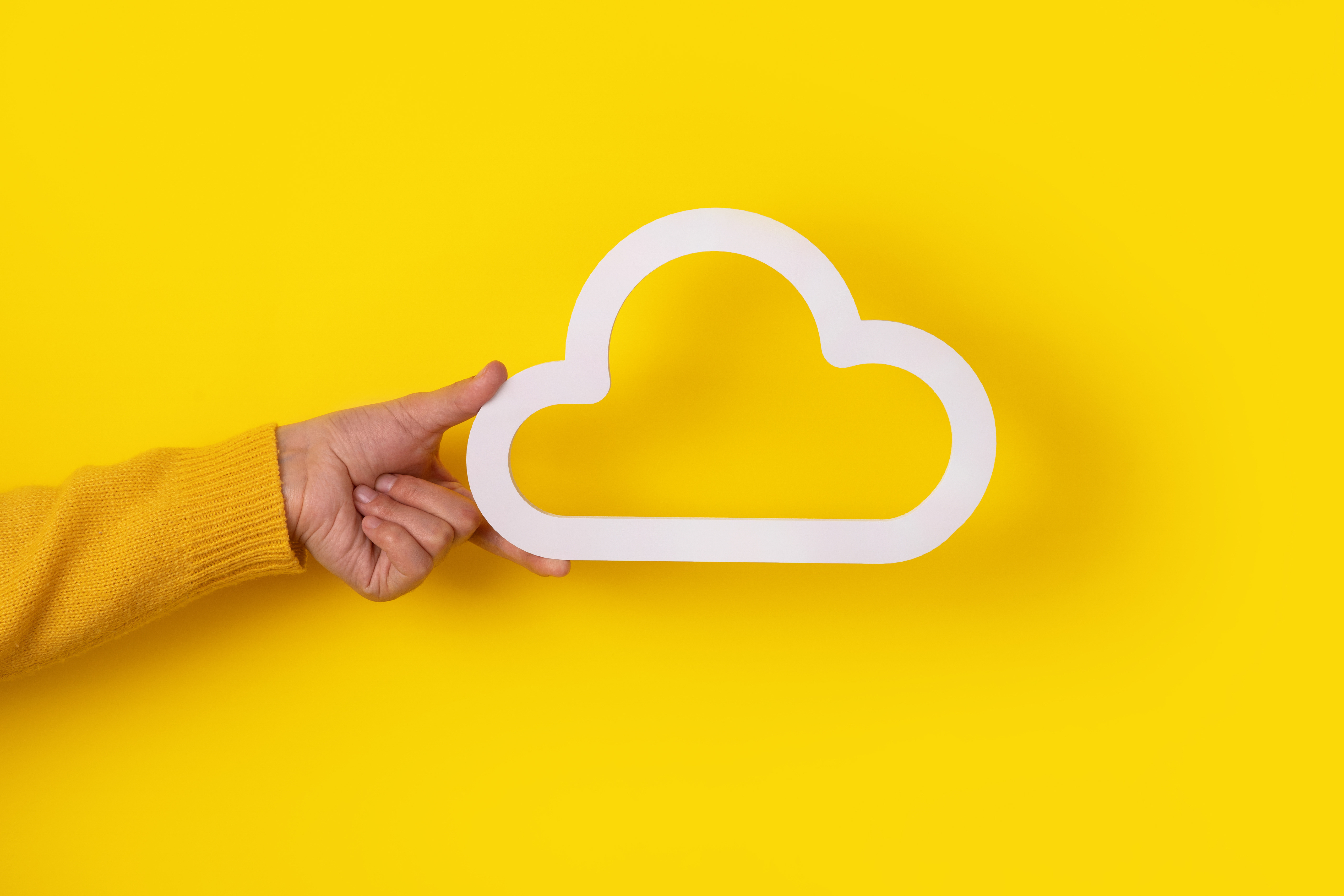 une main tient un nuage aux contours blancs sur fond jaune