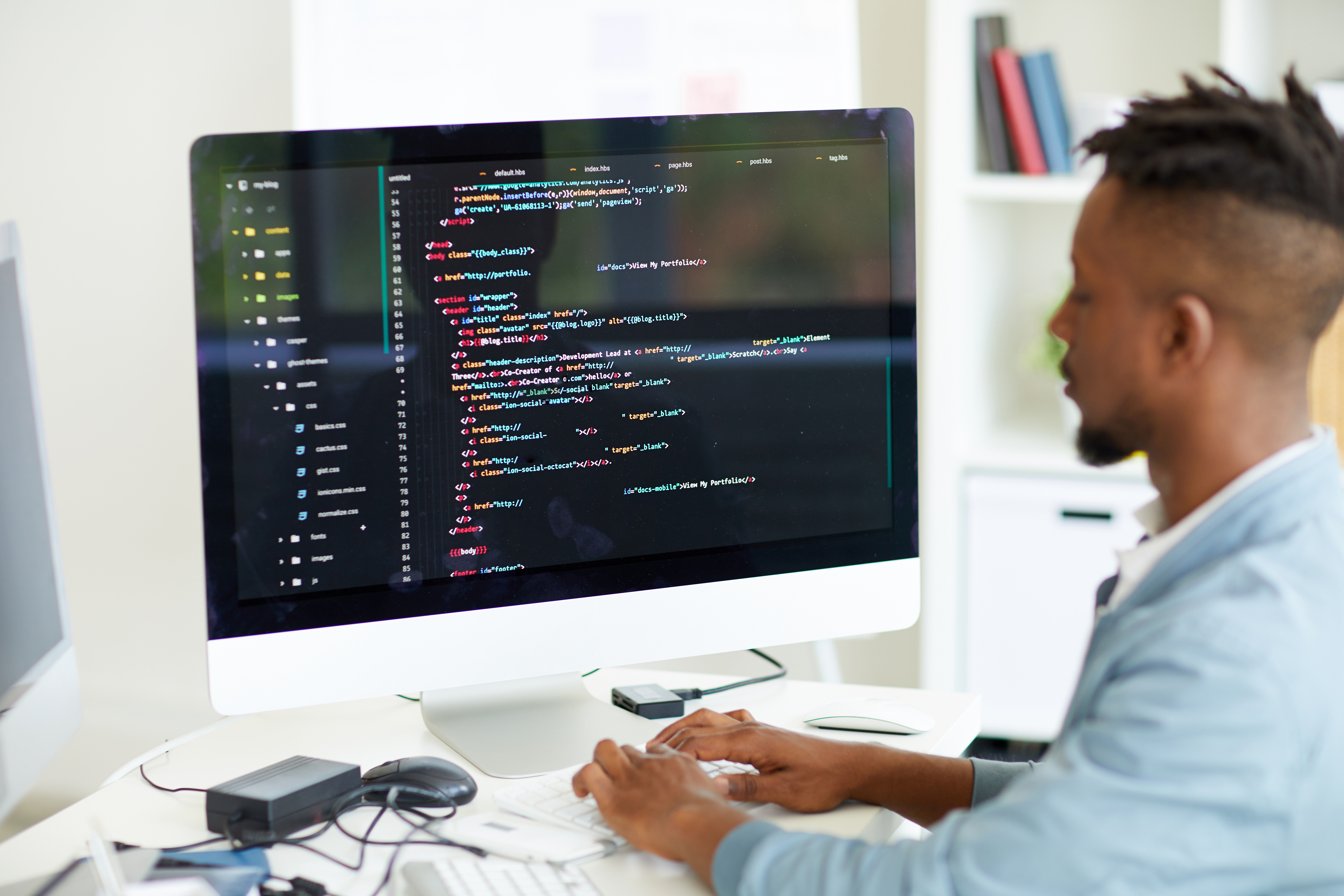 un homme est face à son ordinateur dont l'écran affiche des lignes de code